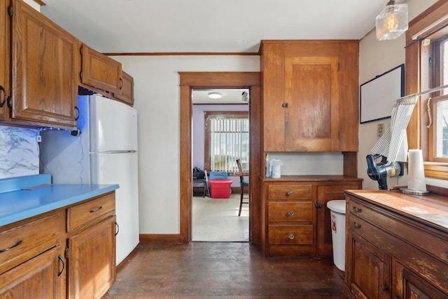 107 Portland St, Fryeburg, ME 04037 - kitchen with light countertops, backsplash, freestanding refrigerator, brown cabinets, and baseboards