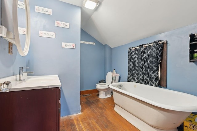 107 Portland St, Fryeburg, ME 04037 - bathroom with visible vents, a freestanding tub, vanity, vaulted ceiling, and wood-type flooring