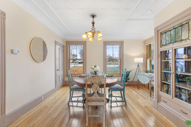 28 Saco Ave, Old Orchard Beach, ME 04064 - dining room with crown molding, baseboards, light wood finished floors, and an inviting chandelier