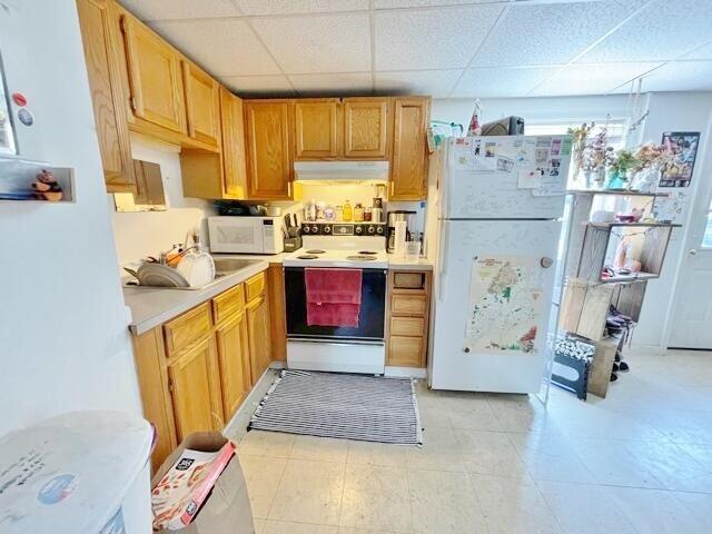 160 Washington Ave, Portland, ME 04101 - kitchen with white appliances, under cabinet range hood, a paneled ceiling, light countertops, and healthy amount of natural light