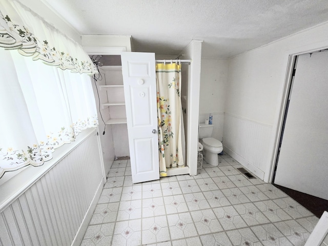 27 Cannard St, Gardiner, ME 04345 - full bath with toilet, wainscoting, tile patterned floors, a textured ceiling, and curtained shower