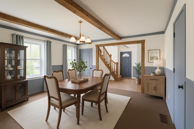 27 Cannard St, Gardiner, ME 04345 - dining area with a chandelier, wainscoting, beamed ceiling, stairs, and light colored carpet