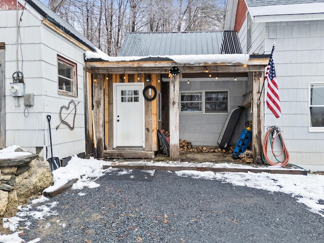 snow covered property entrance with metal roof