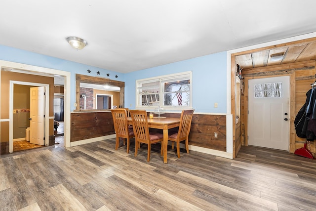 dining space featuring wainscoting, wood walls, and wood finished floors