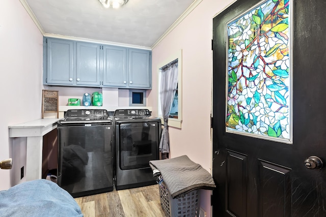 laundry area featuring washing machine and clothes dryer, cabinet space, crown molding, and light wood finished floors