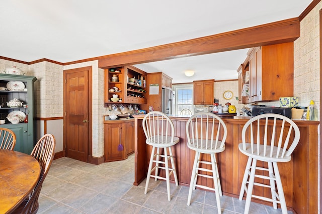 227 Greely Rd, Cumberland, ME 04021 - kitchen with stainless steel fridge with ice dispenser, ornamental molding, brown cabinets, and open shelves