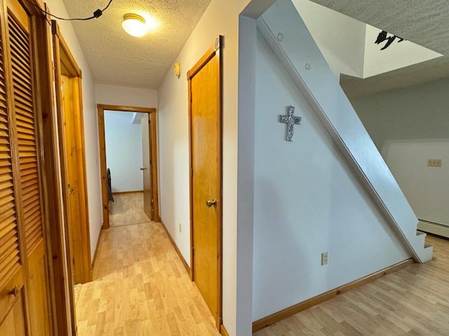 1873 Sly Brook Rd, Eagle Lake, ME 04739 - hallway with light wood-style flooring, a textured ceiling, and baseboards