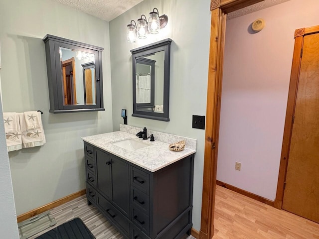 1873 Sly Brook Rd, Eagle Lake, ME 04739 - bathroom featuring vanity, wood finished floors, baseboards, and a textured ceiling
