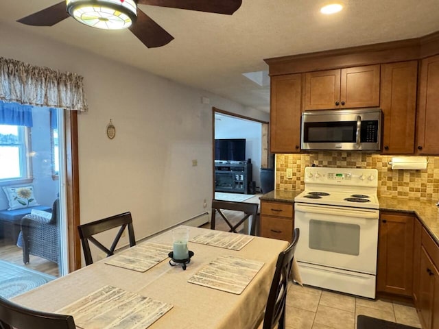 1873 Sly Brook Rd, Eagle Lake, ME 04739 - kitchen with stainless steel microwave, electric range, a ceiling fan, decorative backsplash, and brown cabinets