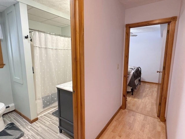 1873 Sly Brook Rd, Eagle Lake, ME 04739 - full bathroom with wood finished floors, toilet, baseboards, curtained shower, and a drop ceiling