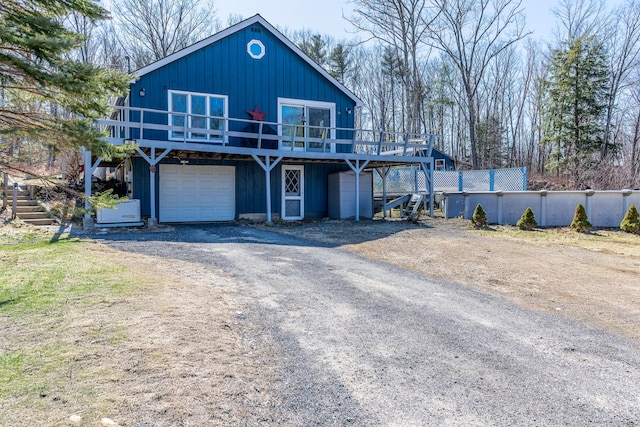 chalet / cabin with a deck, dirt driveway, and a garage