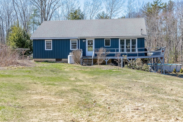 single story home with board and batten siding, a wooden deck, a shingled roof, and a front yard