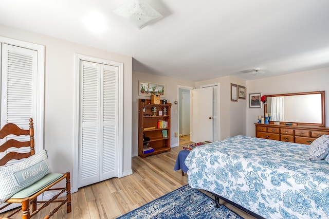 bedroom featuring light wood-style floors, multiple closets, and baseboards