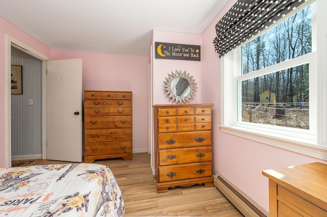bedroom featuring a baseboard radiator, light wood-type flooring, and baseboards