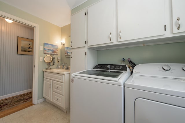 clothes washing area featuring baseboards, laundry area, washer and dryer, and a sink