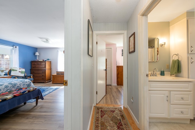 bedroom featuring light wood-style floors, baseboards, and a sink