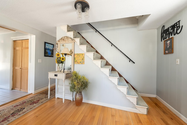 stairs with wood finished floors and baseboards