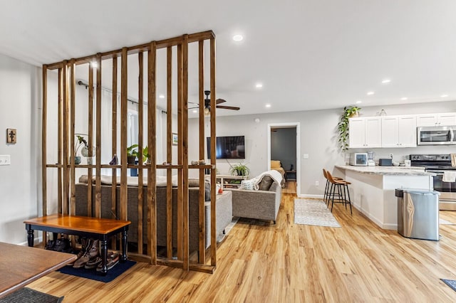 living area featuring baseboards, light wood-style flooring, ceiling fan, and recessed lighting
