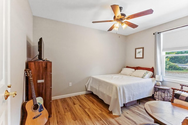 bedroom featuring light wood finished floors, baseboards, and ceiling fan