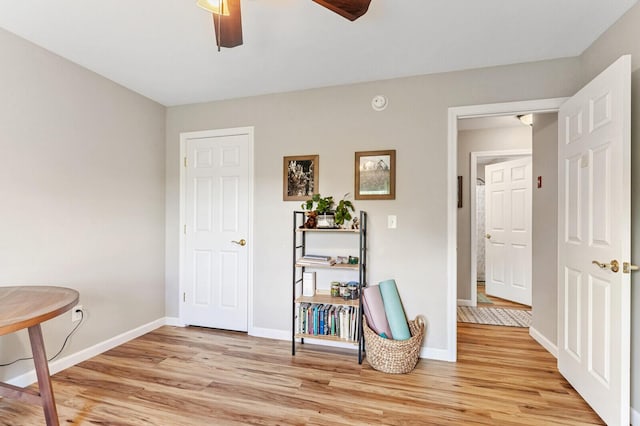 living area with baseboards, light wood-style floors, and ceiling fan