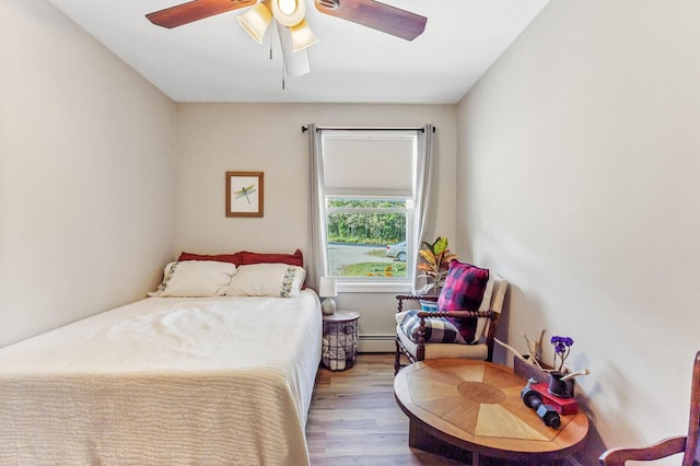bedroom featuring baseboard heating, ceiling fan, and wood finished floors