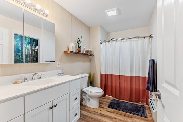 bathroom with a shower with curtain, wood finished floors, vanity, toilet, and baseboard heating