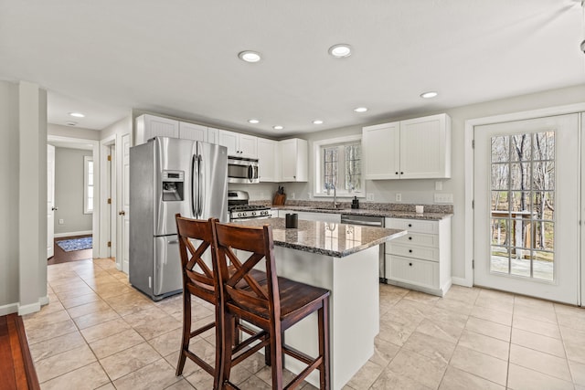 kitchen featuring white cabinets, appliances with stainless steel finishes, stone countertops, recessed lighting, and a kitchen bar