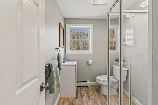 full bath featuring a stall shower, wood finished floors, vanity, a baseboard heating unit, and toilet