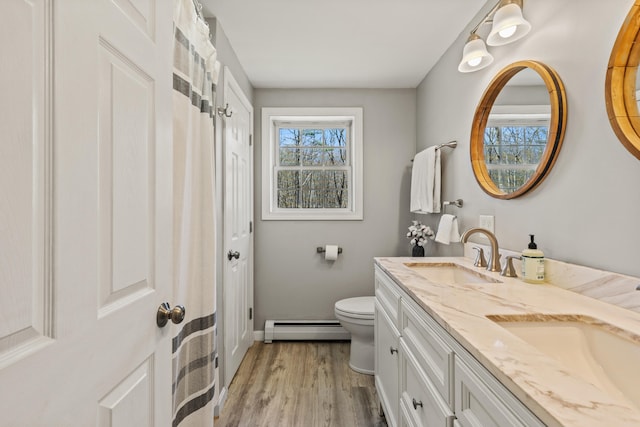 full bathroom with a sink, toilet, baseboards, wood finished floors, and a baseboard radiator