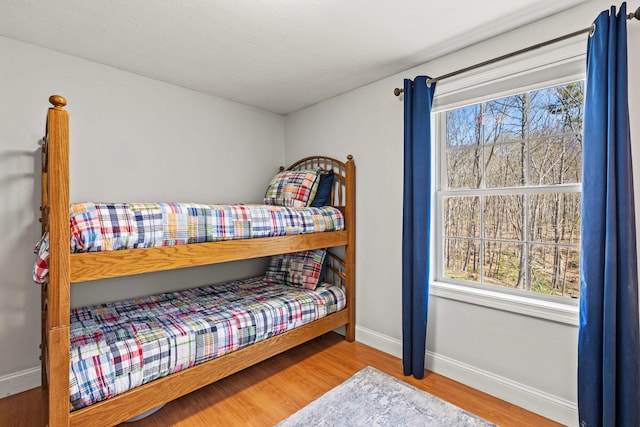 bedroom featuring baseboards, multiple windows, and wood finished floors