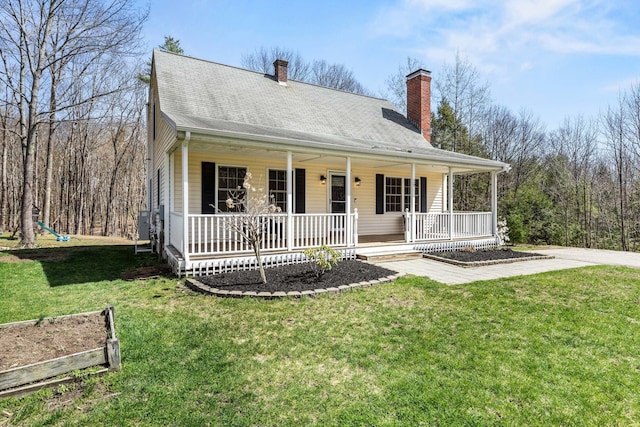 view of front facade with covered porch, a chimney, and a front lawn