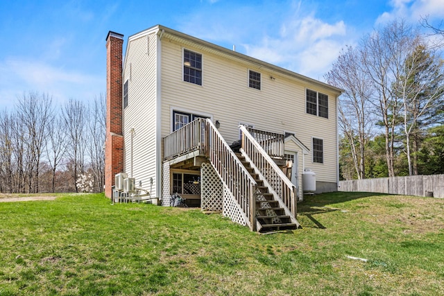 rear view of house featuring a chimney, a lawn, a deck, stairway, and fence