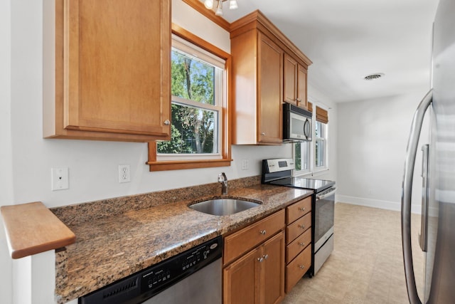 23-25 Deerfield Rd, Portland, ME 04101 - kitchen featuring appliances with stainless steel finishes, a sink, dark stone countertops, brown cabinetry, and baseboards
