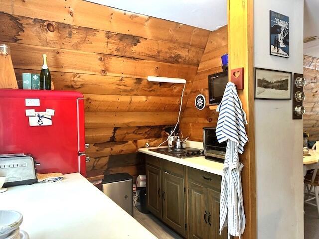 interior space with fridge, black electric cooktop, and wooden walls