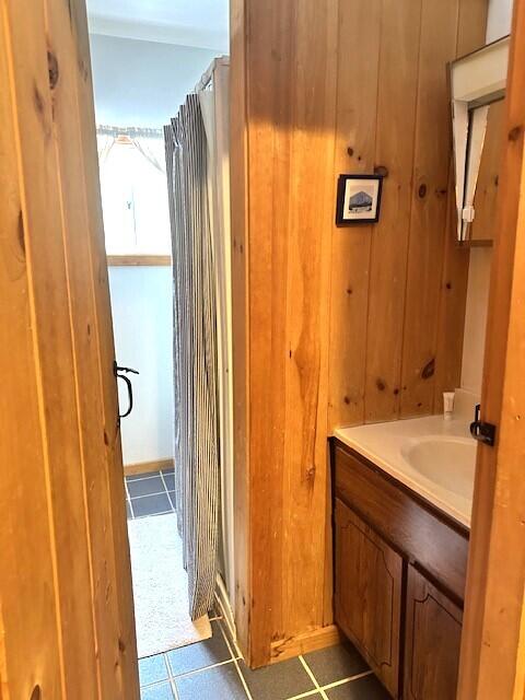 bathroom featuring wood walls, vanity, and tile patterned flooring