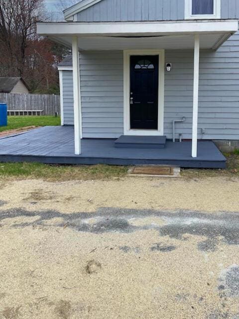 entrance to property with a porch and fence
