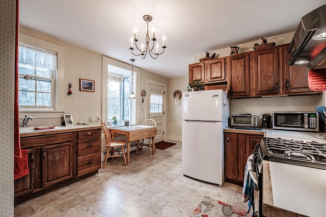 kitchen featuring a baseboard radiator, stainless steel microwave, extractor fan, an inviting chandelier, and freestanding refrigerator