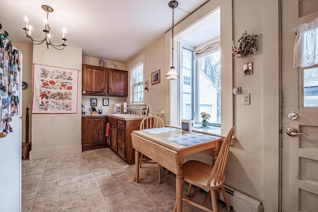 kitchen featuring light countertops, a chandelier, baseboards, a baseboard heating unit, and hanging light fixtures