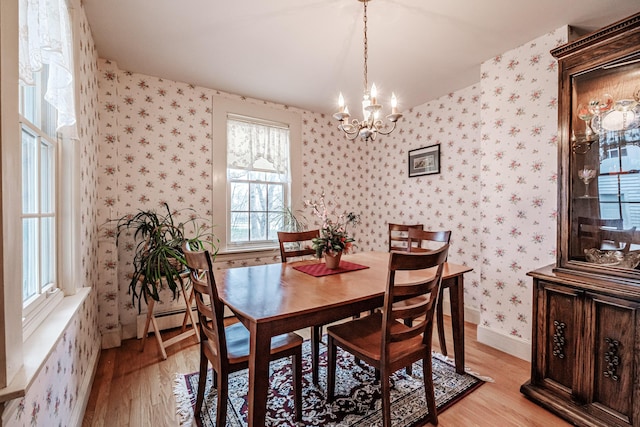 dining space featuring a chandelier, a baseboard radiator, light wood-type flooring, baseboards, and wallpapered walls