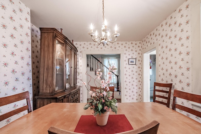 dining space with stairs, wallpapered walls, and a notable chandelier