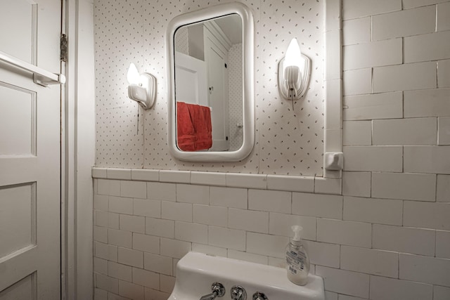 bathroom with a wainscoted wall, wallpapered walls, and tile walls