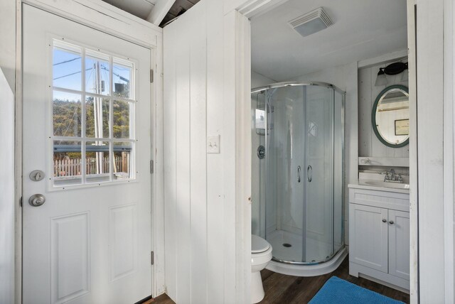 bathroom with vanity, a shower stall, toilet, and visible vents