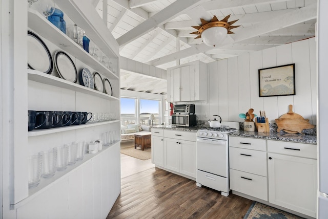 kitchen featuring dark wood-style flooring, white gas stove, dark stone counters, white cabinetry, and lofted ceiling with beams