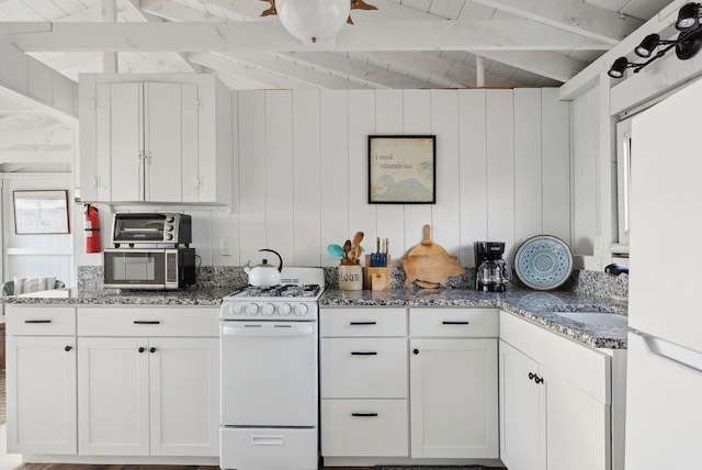 kitchen featuring dark stone counters, white cabinetry, white appliances, and beamed ceiling