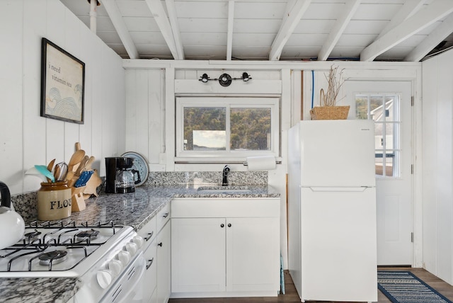 kitchen with beam ceiling, a sink, light stone counters, white cabinets, and white appliances