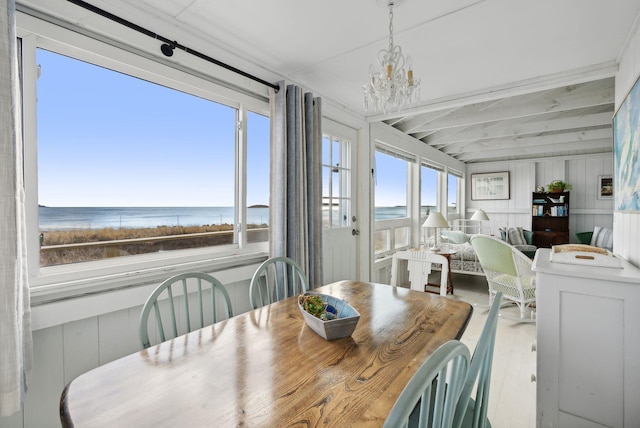 dining area with a water view, wood finished floors, and a chandelier