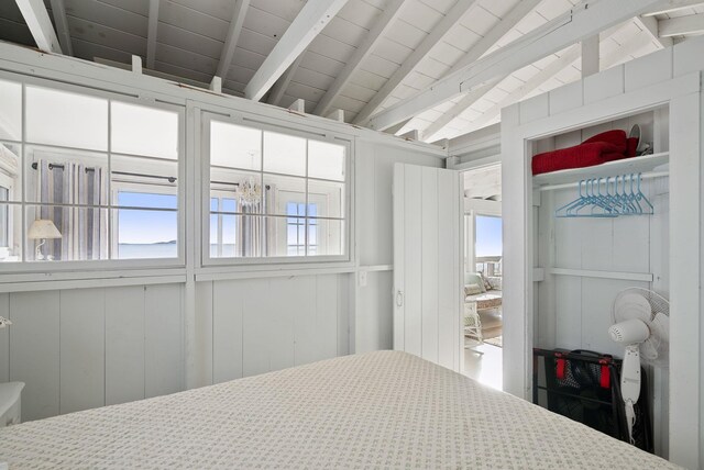 bedroom featuring lofted ceiling with beams and a decorative wall
