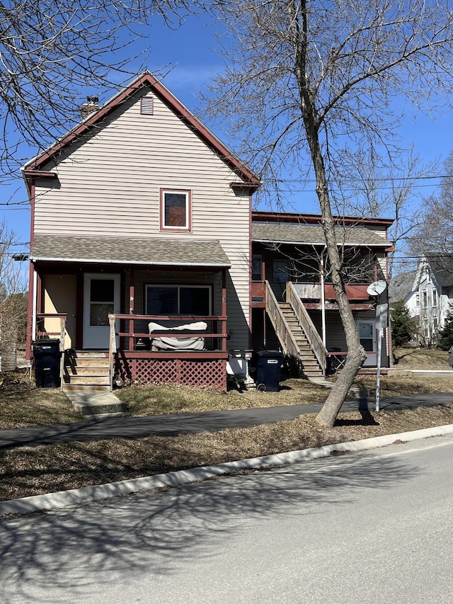 view of front of home with covered porch, stairway, and a chimney