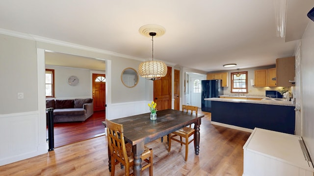 dining room with wainscoting, light wood-style flooring, and ornamental molding