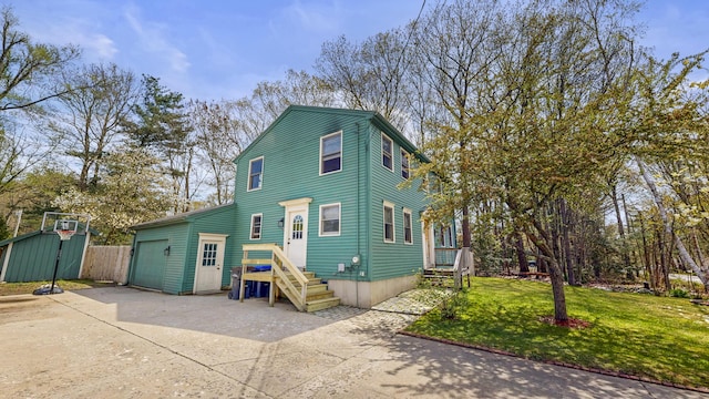 view of front facade with concrete driveway, an outbuilding, a front yard, and a garage